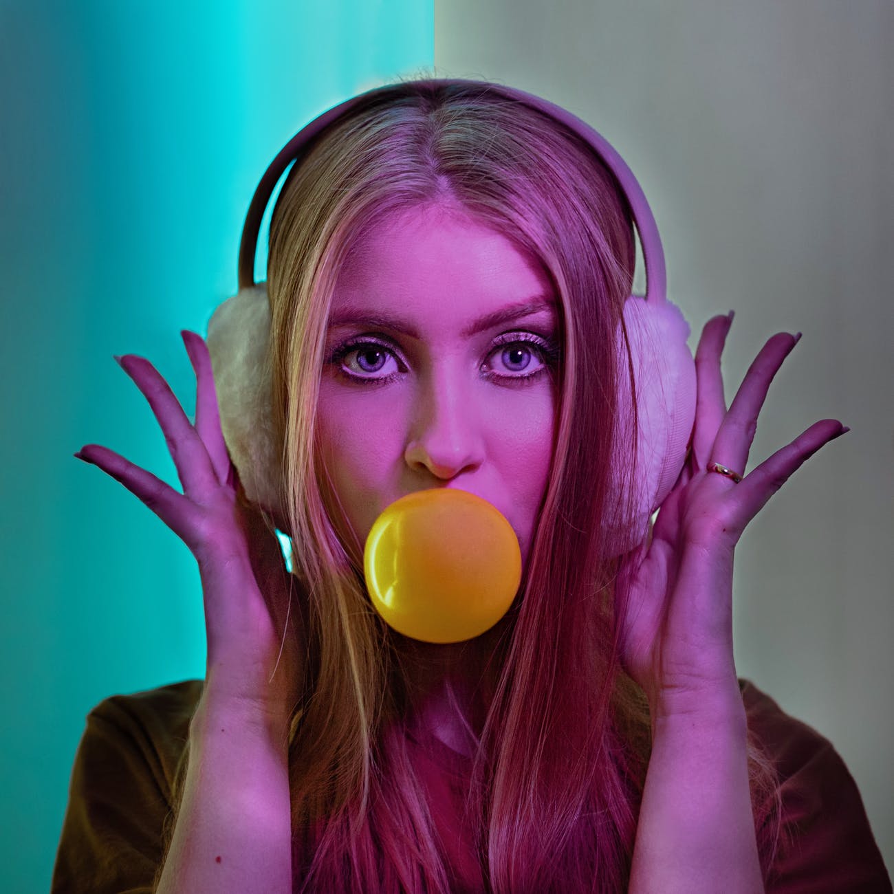 photo of woman wearing ear warmer and blowing bubble gum