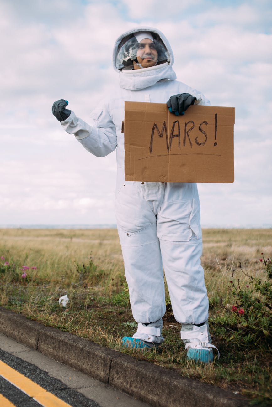 man in an astronaut costume hitchhiking